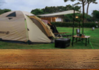 Wooden table top on blur tent camping travel tent and grass field.Fresh and Relax concept.For montage product display or design key visual layout.View of copy space.