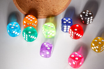 A random arrangement of multicolored dice and a puzzle cup, captured after the dice have been cast.