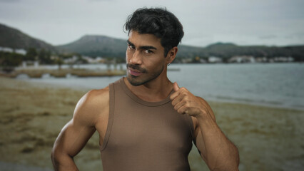 Man performing finger to eyes gesture for watching at sunlit seaside shore with sandy beach and...