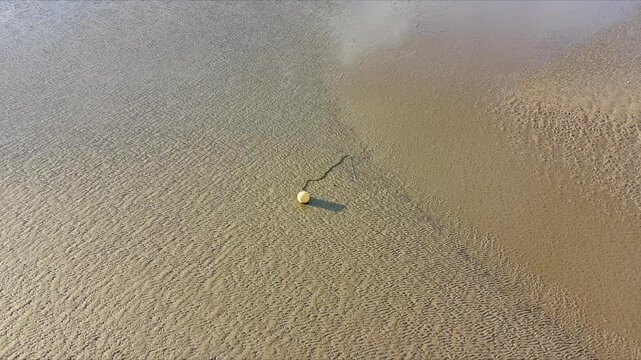 Aerial View of Textured Wet Sand and Yellow Buoy at Low Tide