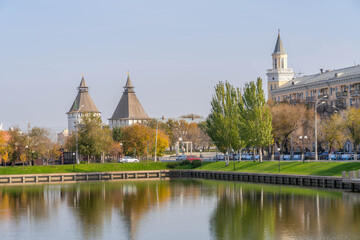 Astrakhan Kremlin towers and Soviet architecture reflected in a pond, framed by autumn trees in...