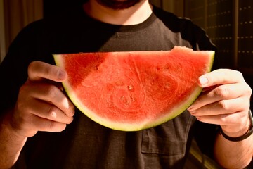 Man holding a juicy red watermelon slice. Symbol of summer, freshness, and healthy fruit rich in vitamins.