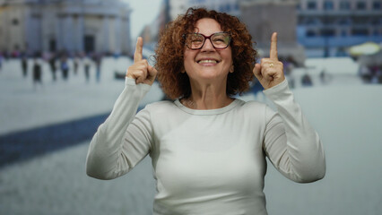 Woman smiling in white shirt pointing upwards in vatican city with iconic st. peter's backdrop,...