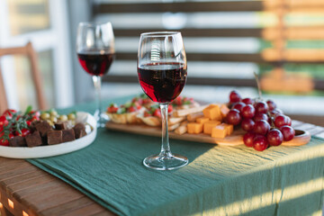 Wine and snack set on wooden terrace table at sunset.