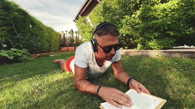 Man on garden lawn immersed in book at sunset