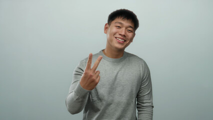Young chinese man in grey sweater over isolated white background expressing gestures with hands,...