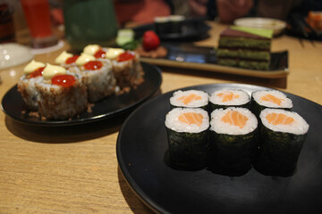 Assortment of Fresh Salmon and Fusion Sushi Rolls on Black Plates at a Japanese Restaurant