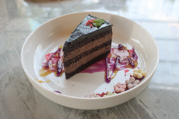 Elegant Slice of Chocolate Layer Cake with Colorful Sauce Garnish on White Plate