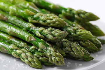 Freshly cooked green asparagus served on a white plate with a sprinkle of salt