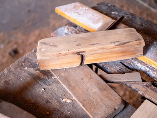 Old wooden hand plane on a vintage woodworking bench in a traditional carpenter's workshop, used for shaping and smoothing wood manually.