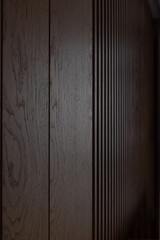 Close-up view of dark brown wood. Brown wooden louvers inside a dark room with grooves that look almost like barcode.