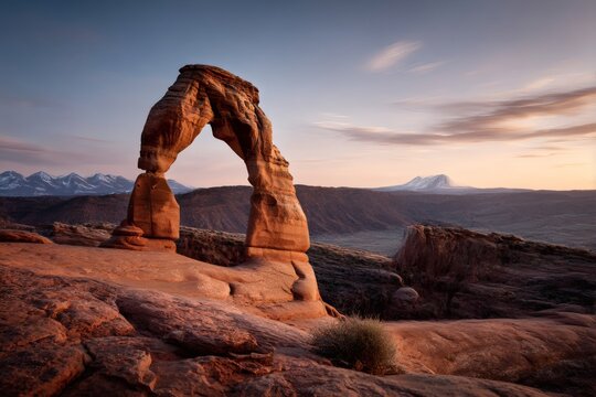 Delicate Arch stands majestically against the sunset sky in Arches National Park, Utah, a stunning red sandstone arch in the vast desert landscape of the American Southwest