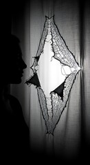 Silhouette of a woman looking through a torn fabric with a diamond shaped opening image