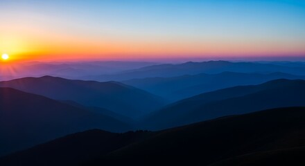 Sunrise over layered blue mountain ranges with orange sky sunset nature