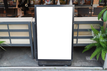 Blank white outdoor advertising stand or sandwich board mock up template. Clear street signage board placed by an outdoor dinning area of a restaurant. Background texture of standee on street.