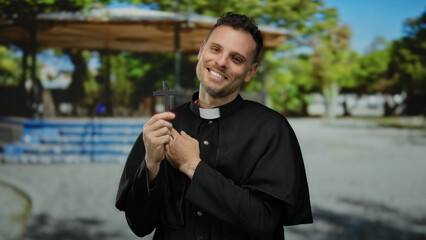 Catholic priest in black robe holding a cross in an outdoor park setting, embodying serenity and...