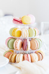 Fresh macarons in a three-tiered tray on a festive table.