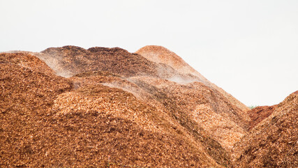 mountains of wood chips against a grey sky