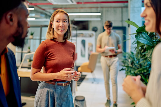 Businesswoman discussing with colleagues in a modern office environment, fostering teamwork and collaboration - Powered by Adobe