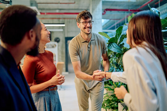 Business partners shaking hands during a meeting in modern office, colleagues looking and smiling