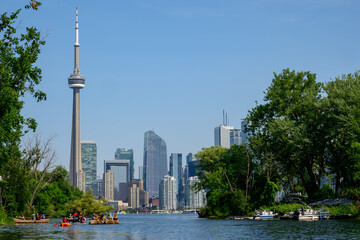 Fototapeta premium paddlers on the water in an urban park with view across harbour to skyscraper skyline shot in Toronto in summer room for text copy space