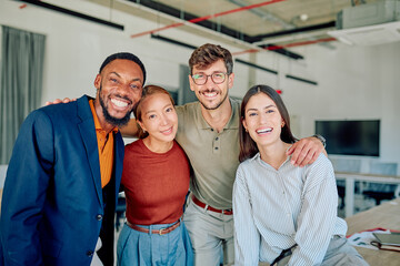 Multi-ethnic businesspeople embracing each other showing teamwork and unity in startup company workplace