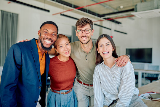 Multi-ethnic businesspeople embracing each other showing teamwork and unity in startup company workplace - Powered by Adobe