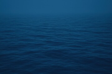 Obraz premium Deep blue ocean waves under a misty sky, a serene and vast water surface reflecting the subtle light