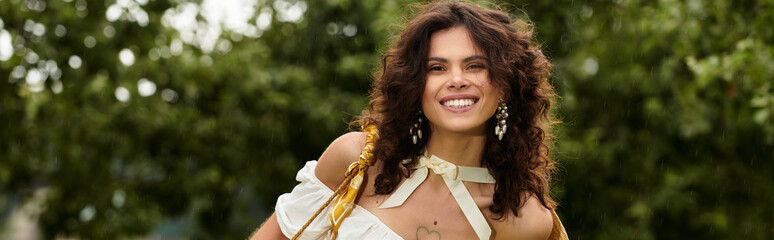 Curly-haired young woman in white dress enjoys nature in a lush green park