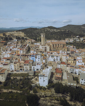 Aerial view of the town's rooftops, where the ancient castle ruins meet the sky, punctuated by the church tower, Cervera del Maestre, Valencian Community, Spain.