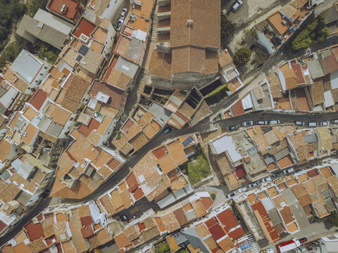 Aerial view of terracotta rooftops cascading around the historic church, creating a warm mosaic under the Spanish sun, Cervera del Maestre, Valencian Community, Spain.