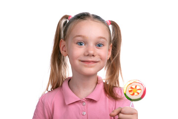 Cheerful young girl in a pink shirt smiling while holding a colorful flower-shaped lollipop against a white background.