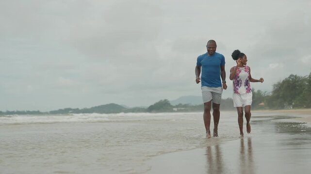 Joyful African American Couple Running Playfully Along the Seashore, Happy Black Man and Woman Enjoying a Romantic Beach Vacation Together