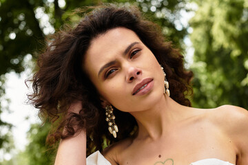 Naklejka premium A young woman with curly hair poses gracefully in a vibrant park, surrounded by nature