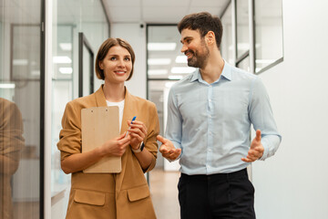 Smiling, successful businesspeople walking and talking in office corridor