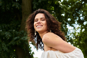 Naklejka premium Curly-haired beauty enjoying a sunny day in a serene village park setting