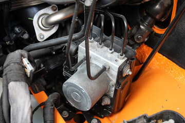 Car ABC system. Close-up of a vehicle ABS pump module with black hydraulic lines, silver aluminum...