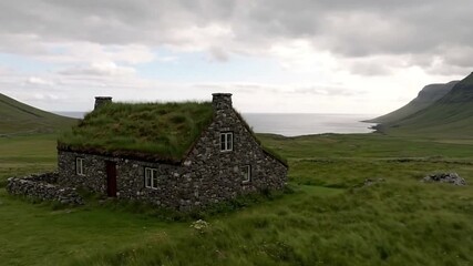 Stone house with grass roof sits amidst a lush hilly landscape near the sea