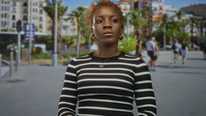 Woman lifts chin amid blurred passersby on sunny city street lined with palm trees; confidence...