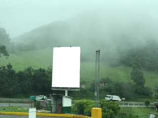 Blank billboard in a misty mountain landscape, ready for ads.