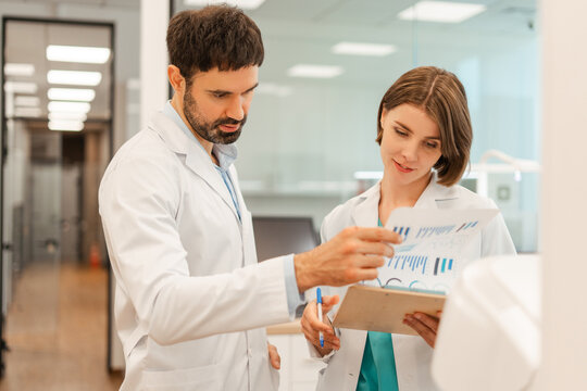 Doctors discussing medical chart with statistics in hospital corridor