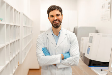 Smiling doctor wearing lab coat and gloves stands in laboratory
