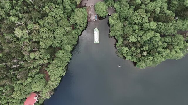 일본 홋카이도 울창한 숲 사이 강물 위에 떠 있는 배 수직 드론 항공뷰 (Top-down aerial drone view of a boat on a river surrounded by lush forest in Hokkaido, Japan)