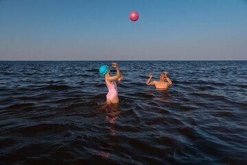 Father and daughter playing with ball in sea on sunny day