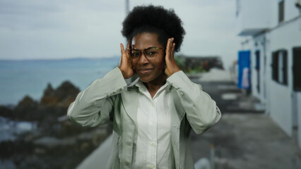 Woman smiling at seaside promenade with ocean in background wearing glasses and green shirt...