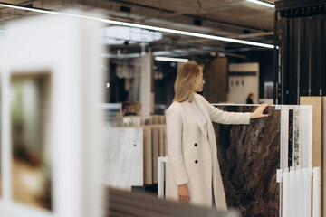 Woman Examining Marble Slabs in a Modern Interior Design Showroom