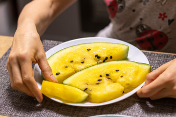 Close up shot of the cut watermelon with yellow flesh on ceramic plate. Food