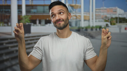 Hispanic young man outdoors in an urban street making air quote gestures, expressing sarcastic...