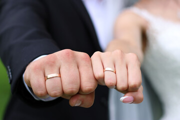 The hands of the newlyweds with wedding rings are clenched into fists.