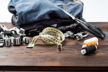Metal thimble with sewing tools and clothing background.